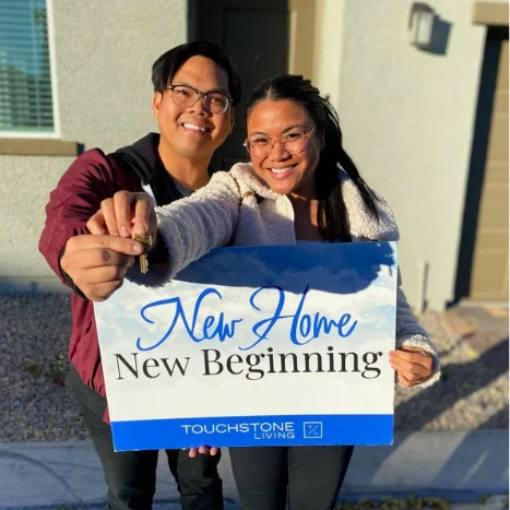 Happy couple dangling keys and holding a sign that reads: New Home, New Beginning